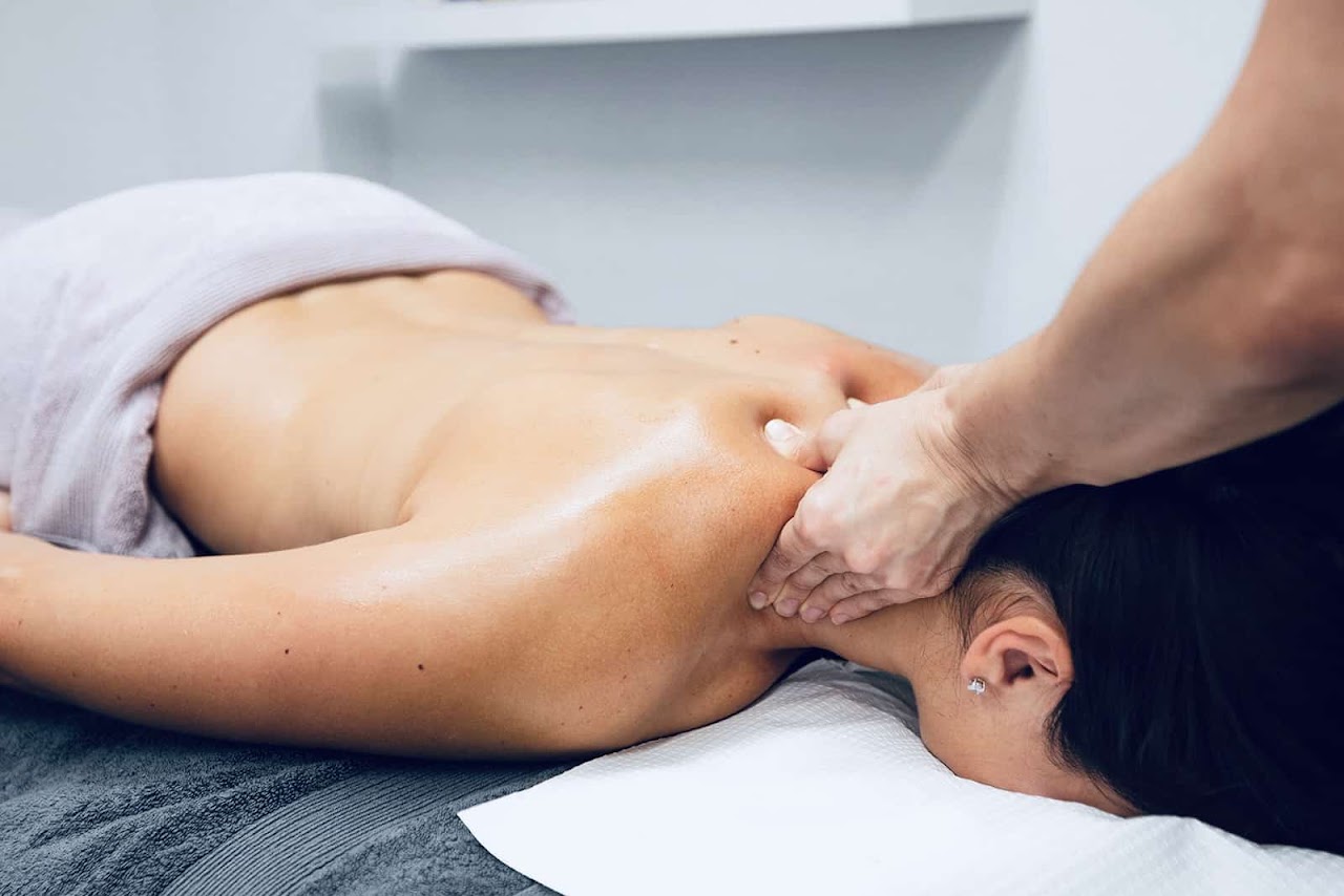 Masajista terapéutico profesional aplicando presión en contracturas de espalda